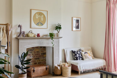 Photo of a large bohemian children’s room for girls in London with white walls, light hardwood flooring, beige floors and a chimney breast.