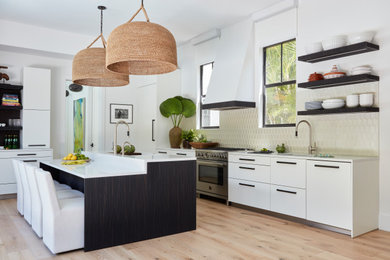 Example of a large trendy u-shaped light wood floor open concept kitchen design in Miami with an undermount sink, flat-panel cabinets, white cabinets, quartz countertops, white backsplash, glass tile backsplash, paneled appliances, an island and white countertops