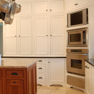 Mid-sized farmhouse kitchen pantry ideas - Example of a mid-sized country u-shaped ceramic floor kitchen pantry design in Wichita with an undermount sink, beaded inset cabinets, white cabinets, granite countertops, paneled appliances and an island