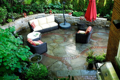 This is an example of a small eclectic backyard patio in Montreal with natural stone pavers and an awning.