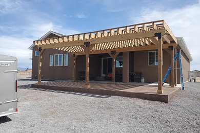 This is an example of a large craftsman wood railing back porch design in Denver with a pergola.
