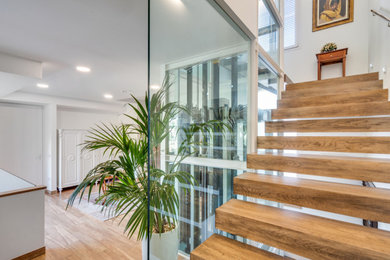 Foto de escalera suspendida contemporánea grande sin contrahuella con escalones de madera y barandilla de metal