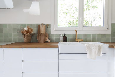 Idées déco pour une grande cuisine blanche et bois scandinave en L fermée avec un évier 2 bacs, des portes de placard blanches, un plan de travail en bois, une crédence verte, une crédence en céramique, un électroménager blanc, carreaux de ciment au sol, îlot, un sol blanc, un plan de travail marron et fenêtre au-dessus de l'évier.