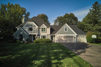 Example of a large transitional multicolored two-story vinyl and clapboard house exterior design in Minneapolis with a hip roof, a shingle roof and a black roof