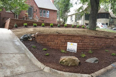 This is an example of a large country front yard garden in Omaha with a retaining wall and brick pavers.