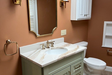 This is an example of a mid-sized transitional bathroom in Boston with shaker cabinets, green cabinets, an alcove tub, an alcove shower, a one-piece toilet, beige tile, glass tile, brown walls, wood-look tile, an undermount sink, engineered quartz benchtops, brown floor, a sliding shower screen, multi-coloured benchtops, a niche, a single vanity and a built-in vanity.