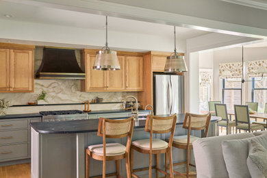 Inspiration for a mid-sized transitional galley medium tone wood floor and brown floor open concept kitchen remodel in Austin with a single-bowl sink, flat-panel cabinets, soapstone countertops, marble backsplash, stainless steel appliances, an island, gray countertops, light wood cabinets and multicolored backsplash