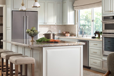 Example of a classic light wood floor kitchen design in San Francisco with raised-panel cabinets, quartz countertops, beige backsplash, stone tile backsplash, stainless steel appliances, an island, beige countertops and blue cabinets