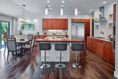Inspiration for a mid-sized contemporary eat-in kitchen in Dallas with an undermount sink, flat-panel cabinets, medium wood cabinets, quartz benchtops, white splashback, ceramic splashback, stainless steel appliances, medium hardwood floors and with island.