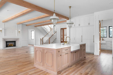 Open concept kitchen - large country single-wall light wood floor open concept kitchen idea in St Louis with a farmhouse sink, shaker cabinets, medium tone wood cabinets, quartzite countertops, white backsplash, stainless steel appliances, an island and white countertops