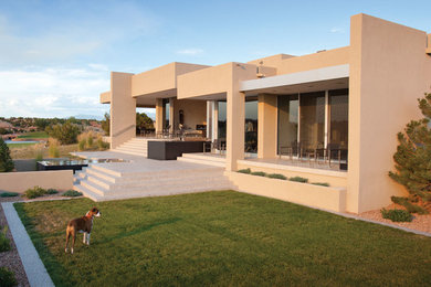 Example of a large minimalist backyard patio fountain design in Albuquerque with a roof extension