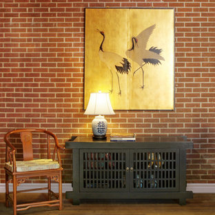 Immagine di un piccolo soggiorno etnico stile loft con libreria, pareti rosse, pavimento in legno massello medio, nessun camino e nessuna TV