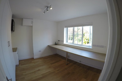 Kleines Klassisches Arbeitszimmer mit weißer Wandfarbe, braunem Holzboden und Einbau-Schreibtisch in Sonstige