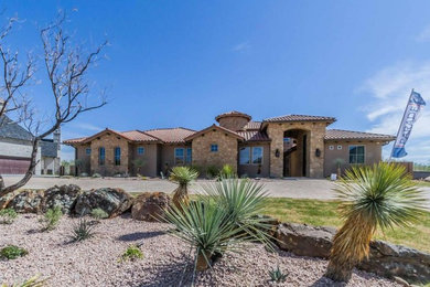 Example of a large southwest beige two-story stucco house exterior design in Austin with a hip roof and a tile roof