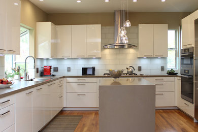 Eat-in kitchen - mid-sized contemporary u-shaped medium tone wood floor and brown floor eat-in kitchen idea in San Francisco with a single-bowl sink, flat-panel cabinets, white cabinets, quartz countertops, white backsplash, glass tile backsplash, stainless steel appliances and an island