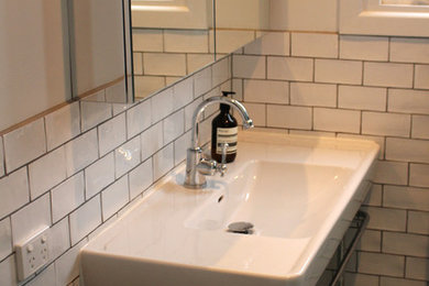 Photo of a small contemporary master bathroom in Melbourne with a pedestal sink, flat-panel cabinets, a curbless shower, white tile, white walls and ceramic floors.