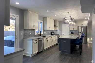 Large minimalist l-shaped vinyl floor and gray floor eat-in kitchen photo in Chicago with an undermount sink, recessed-panel cabinets, white cabinets, gray backsplash, ceramic backsplash, stainless steel appliances, an island, gray countertops and quartzite countertops