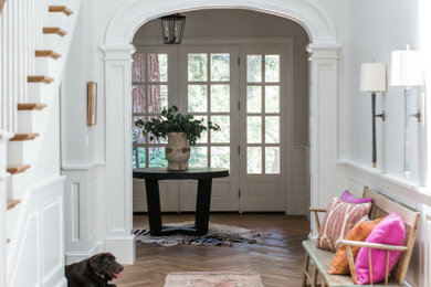 Example of a classic medium tone wood floor foyer design in Other with white walls