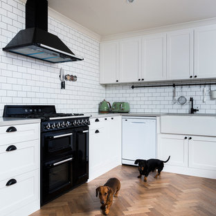 Mid-sized eclectic kitchen pantry designs - Mid-sized eclectic l-shaped medium tone wood floor kitchen pantry photo in Canberra - Queanbeyan with a farmhouse sink, shaker cabinets, white cabinets, quartz countertops, white backsplash, subway tile backsplash, black appliances and an island
