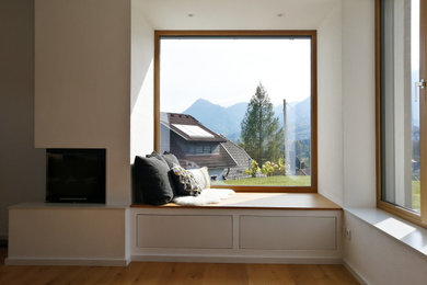 Diseño de sala de estar cerrada con chimenea de esquina y suelo de madera en tonos medios