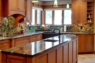Example of a large classic u-shaped travertine floor eat-in kitchen design in Other with a farmhouse sink, recessed-panel cabinets, medium tone wood cabinets, quartzite countertops, green backsplash, ceramic backsplash, stainless steel appliances and an island