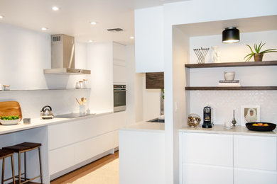 Mid-sized minimalist galley kitchen photo in Atlanta with flat-panel cabinets, white cabinets, quartz countertops and white backsplash
