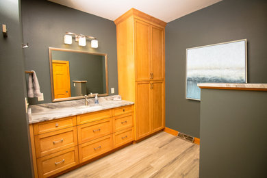 Example of a transitional master gray tile and porcelain tile vinyl floor and double-sink bathroom design in Milwaukee with shaker cabinets, light wood cabinets, a bidet, green walls, an undermount sink, granite countertops, a hinged shower door, multicolored countertops and a built-in vanity