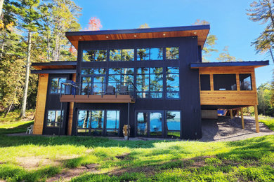 Modern black wood and board and batten house exterior idea in Other with a shed roof, a metal roof and a black roof