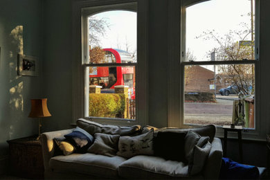 Photo of a mid-sized traditional living room in London with a library and green walls.