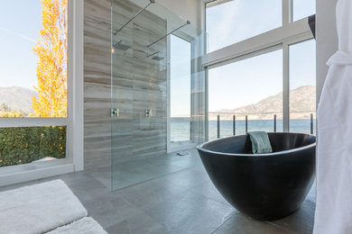 Example of a large beach style master brown tile and stone tile cement tile floor and gray floor bathroom design in Other with flat-panel cabinets, white cabinets, a two-piece toilet, white walls, an integrated sink and solid surface countertops