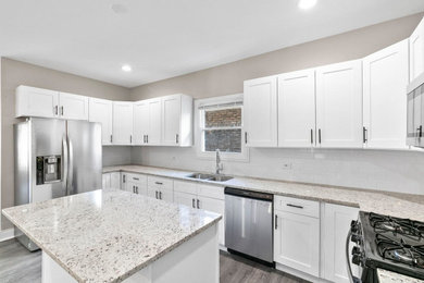 Mid-sized minimalist u-shaped laminate floor and brown floor eat-in kitchen photo in Chicago with an undermount sink, shaker cabinets, white cabinets, granite countertops, white backsplash, ceramic backsplash, stainless steel appliances, an island and beige countertops