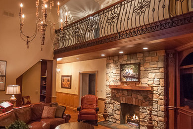 Foto de salón tradicional de tamaño medio con paredes beige, suelo de madera en tonos medios, todas las chimeneas, marco de chimenea de piedra y televisor en una esquina