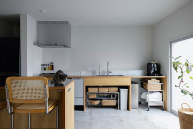 Photo of a small country single-wall open plan kitchen in Other with an undermount sink, open cabinets, light wood cabinets, stainless steel benchtops, grey splashback, terra-cotta splashback, coloured appliances, cement tiles, with island, green floor, brown benchtop and wallpaper.