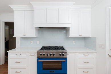 Example of a small transitional galley medium tone wood floor and brown floor enclosed kitchen design in Detroit with an undermount sink, recessed-panel cabinets, white cabinets, quartz countertops, white backsplash, glass tile backsplash, paneled appliances and no island