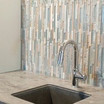 Basement Bar with Glass Water Tile, Corian Countertops, and Chrome Faucet