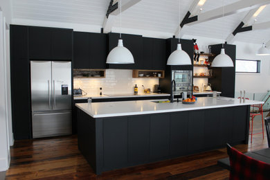 トロントにある中くらいな北欧スタイルのおしゃれなキッチン (アンダーカウンターシンク、フラットパネル扉のキャビネット、黒いキャビネット、クオーツストーンカウンター、白いキッチンパネル、サブウェイタイルのキッチンパネル、シルバーの調理設備、無垢フローリング、茶色い床、白いキッチンカウンター、板張り天井) の写真