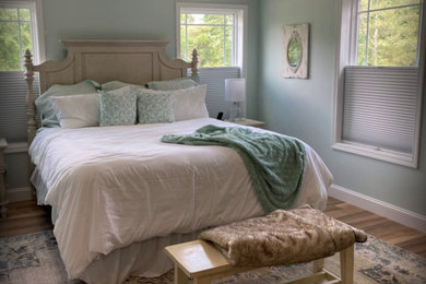 Diseño de dormitorio principal de estilo de casa de campo grande con paredes azules, suelo laminado y suelo marrón