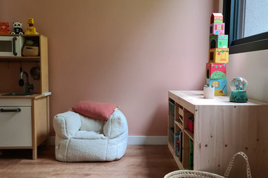 Inspiration pour une chambre de fille de 1 à 3 ans design avec un mur rose, sol en stratifié et un sol marron.