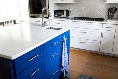 Example of a mid-sized transitional u-shaped medium tone wood floor and brown floor eat-in kitchen design in Charlotte with a double-bowl sink, shaker cabinets, blue cabinets, quartz countertops, white backsplash, marble backsplash, stainless steel appliances, an island and white countertops