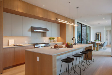 Inspiration for a contemporary galley eat-in kitchen in San Francisco with an undermount sink, flat-panel cabinets, medium wood cabinets, quartz benchtops, white splashback, panelled appliances, medium hardwood floors, with island, brown floor and white benchtop.