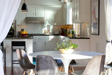 Eat-in kitchen - large modern eat-in kitchen idea in Los Angeles with an undermount sink, raised-panel cabinets, white cabinets, granite countertops, white backsplash, stainless steel appliances and an island