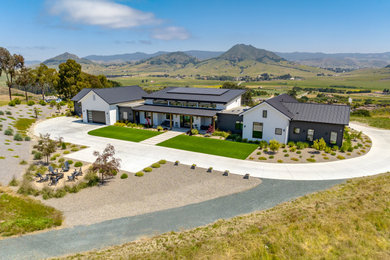 Example of a country gray one-story board and batten house exterior design in San Luis Obispo with a metal roof and a black roof