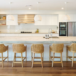 Inspiration for a beach style kitchen in Sunshine Coast with an undermount sink, marble benchtops, white splashback, porcelain splashback, stainless steel appliances, medium hardwood floors, brown floor and multi-coloured benchtop.