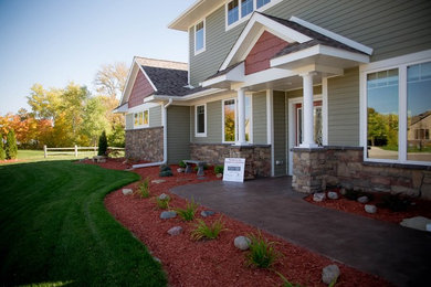 Large elegant beige two-story wood house exterior photo in Other with a shingle roof and a clipped gable roof