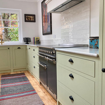 Light green cottage style kitchen with white worktops and kitchen island