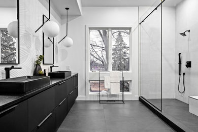 Immagine di una grande stanza da bagno minimalista con ante lisce, ante nere, piastrelle bianche, top in granito, doccia aperta, nicchia e due lavabi