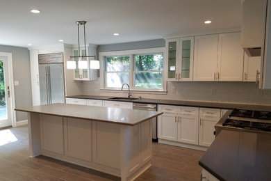 Open concept kitchen - transitional l-shaped ceramic tile and beige floor open concept kitchen idea in New York with a drop-in sink, recessed-panel cabinets, white cabinets, granite countertops, white backsplash, ceramic backsplash, stainless steel appliances and an island