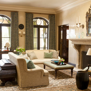 Modelo de salón abierto, mediterráneo, grande, con paredes beige, suelo de madera oscura, chimenea tradicional y marco de chimenea de piedra