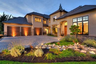 Inspiration for a large mediterranean beige two-story stone house exterior remodel in Seattle with a hip roof and a shingle roof