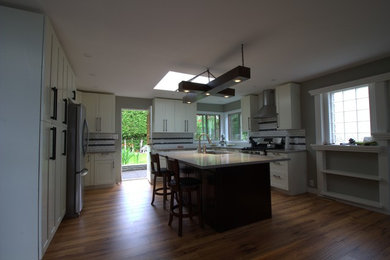 Large trendy eat-in kitchen photo in Vancouver with an undermount sink, shaker cabinets, white cabinets, quartz countertops, subway tile backsplash, stainless steel appliances and an island